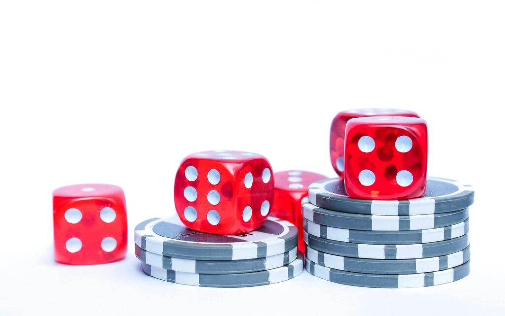Jetons de casino empilés avec des dés rouges, illustrant les jeux de casino en ligne, les mises et les gains potentiels.
